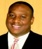 A photograph of a man in his late 20s or early thirties, wearing a suit and tie